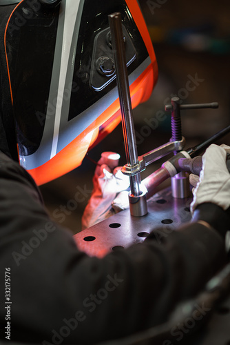 A tig welder works in a workshop and welds a metal pipe