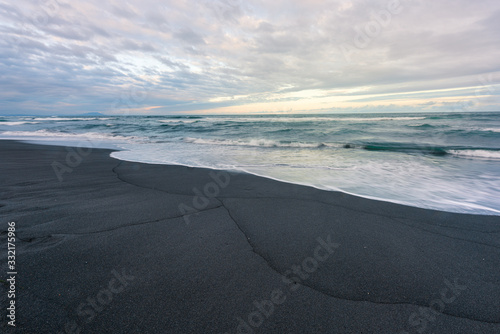 Pacific ocean coast black sand beach and rocks in the water. Kamchatka, Russia