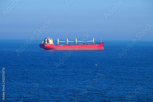 red cargo ship at sea on the horizon