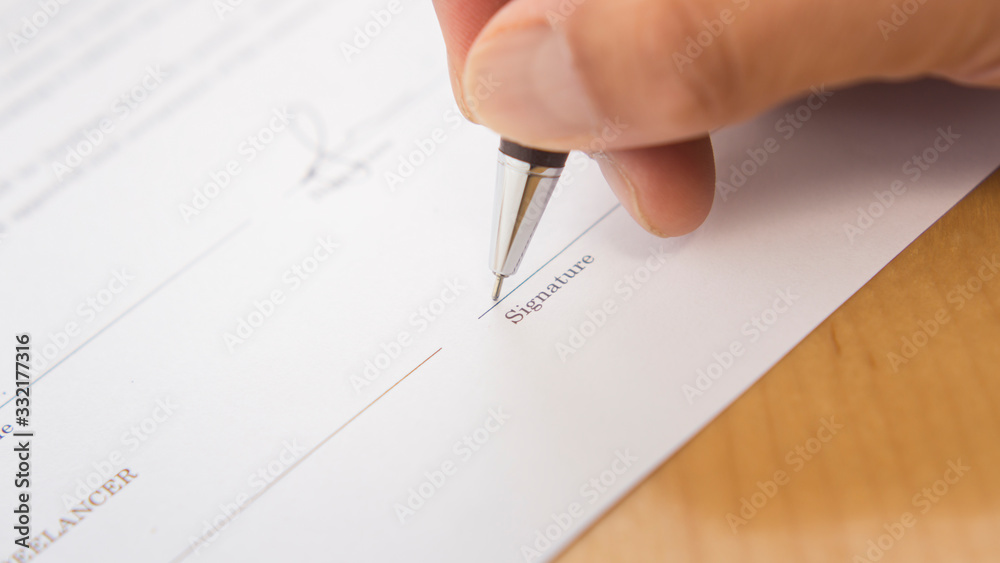 hand signing a document with pen. Signing a contract. Hand holding a pen. hand signing a document with pen. Signing a contract. Hand holding a pen.
