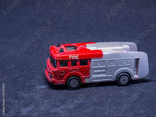 Old dusty fire truck toy car on gray background