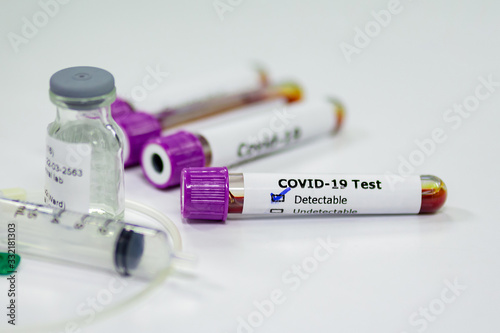 Blood sample tube of coronavirus or covid-19 disease with vaccine testing syringe. Medical and microbiologist science concepth photo.