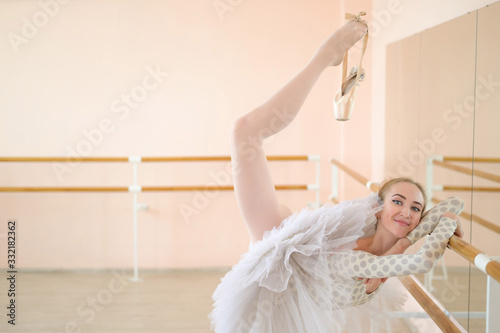 Beautiful young ballerina is rehearsing a solo part in a class with a barre. Slender graceful dancer is engaged before the performance.