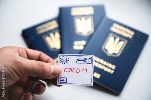 A man holds in his hand a drawn stamp with the inscription "coronavirus" on the background of foreign passports.