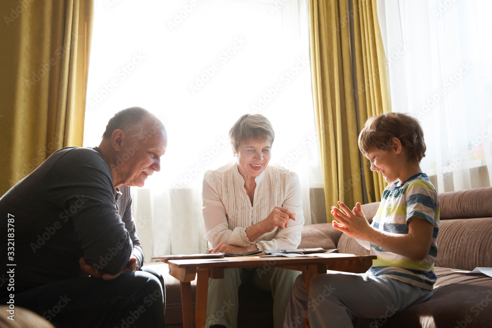 Obraz premium grandparents with grandson playing board game together at home. quarantine. health concept. Corona Virus. Family having fun playing at home