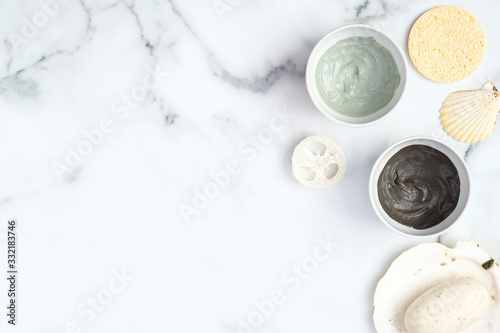 Natural organic SPA cosmetic products set. Top view clay facial mask in bowls, sponge, homemade soap on marble background. Face skin care and beauty treatment concept