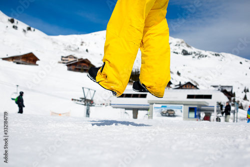 Jumping man in yellow ski pants on snow background. Enjoying activites in winter time. 