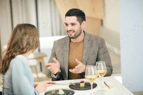 Minimal high angle portrait of modern couple talking and gesturing while enjoying romantic date in cafe, copy space