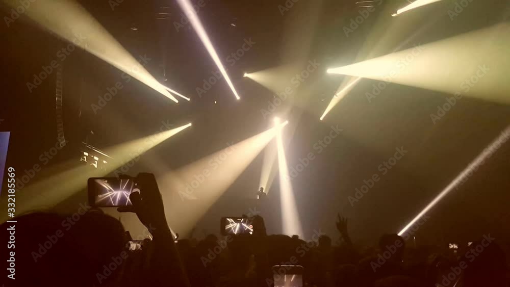 Happy people dance in nightclub party concert and listen to music from DJ on the stage in background. Cheerful crowd celebrate Christmas and New Year party 2018. Young people lifestyle and nightlife.