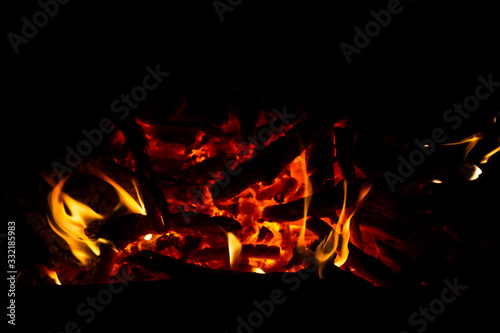 Red coals with fire on a black background. Burning coals and wood in the fire. Burning wood to keep warm and heat.