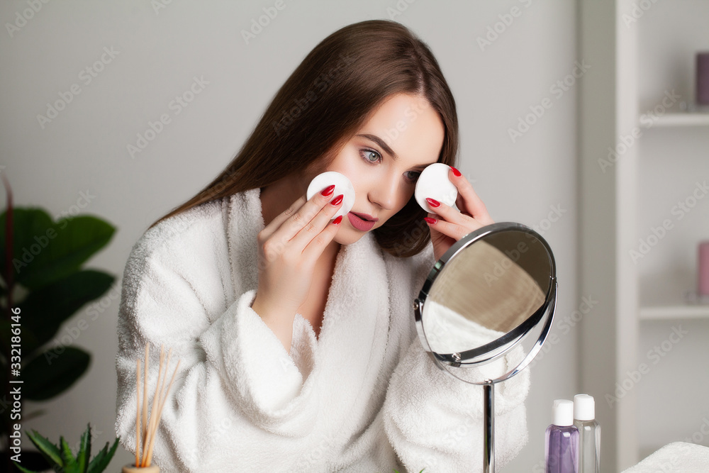 Cute young woman puts makeup on the face in the bathroom Cute young woman puts makeup on the face in the bathroom