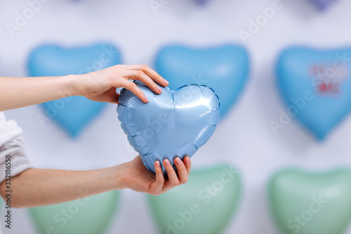 The woman holds the blue balloon in the form of a heart on many hearts background. valentines day. selective focus