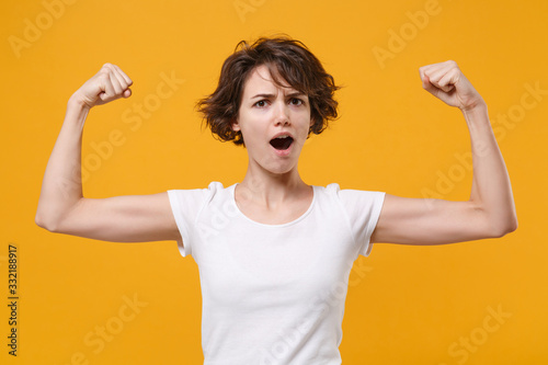 Fotobehang Strong young brunette woman girl in white t-shirt posing isolated on yellow orange background studio portrait