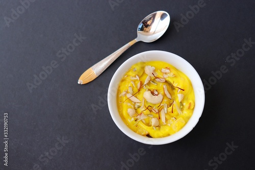 Indian dessert - Shrikhand or Srikhand is sweet yogurt dessert. Mostly eaten during Gudi Padwa festival with Puris. Garnished with dry fruits and saffron. Along with copy space. photo