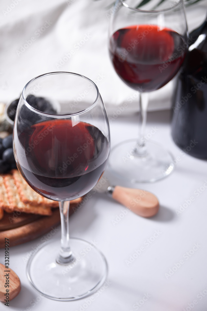 Two glasses of red wine and plate with assorted cheese, fruit and other snacks for party Two glasses of red wine and plate with assorted cheese, fruit and other snacks for party