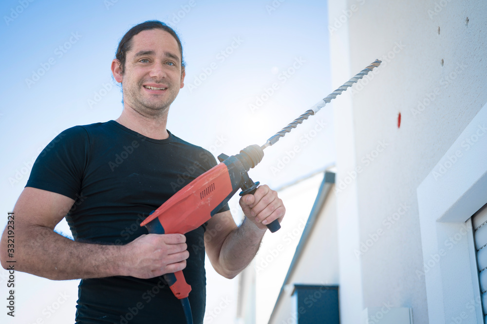 freundlicher Handwerker mit der großen Bohrmaschine freundlicher Handwerker mit der großen Bohrmaschine
