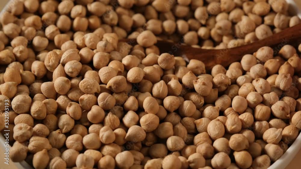 Dry uncooked chickpea falling from spoon into white bowl. Food video macro Dry uncooked chickpea falling from spoon into white bowl. Food video macro
