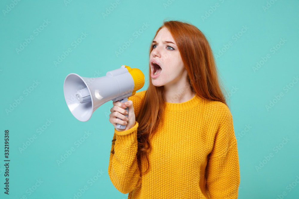 Shocked young redhead woman girl in yellow knitted sweater posing isolated on blue turquoise background studio portrait. People emotions lifestyle concept. Mock up copy space. Scream in megaphone. Shocked young redhead woman girl in yellow knitted sweater posing isolated on blue turquoise background studio portrait. People emotions lifestyle concept. Mock up copy space. Scream in megaphone.