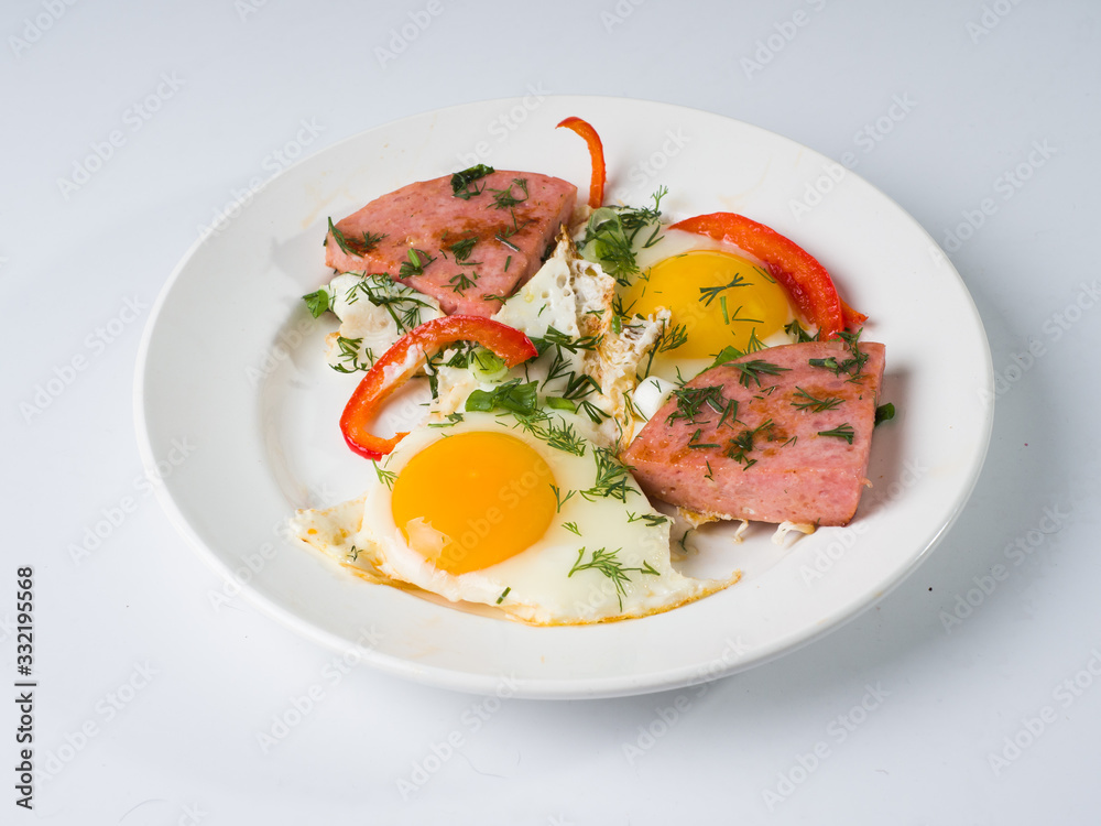 Fried sausage fried eggs on a white round plate. Side view