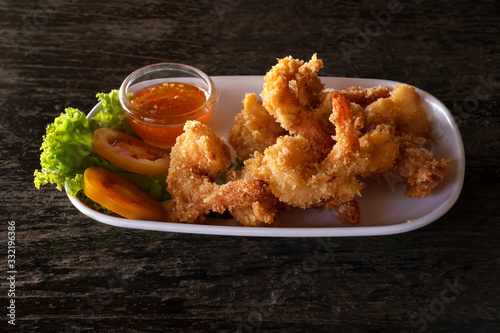Fried prawns in breadcrumbs with sauce on white plate. seafood on dark background.
