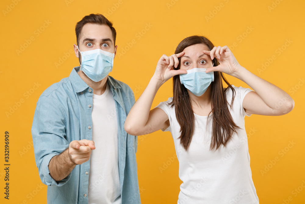 Two people in sterile face masks white t-shirts isolated on yellow background studio. Epidemic pandemic rapidly spreading coronavirus 2019-ncov medicine flu virus ill sick disease treatment concept.