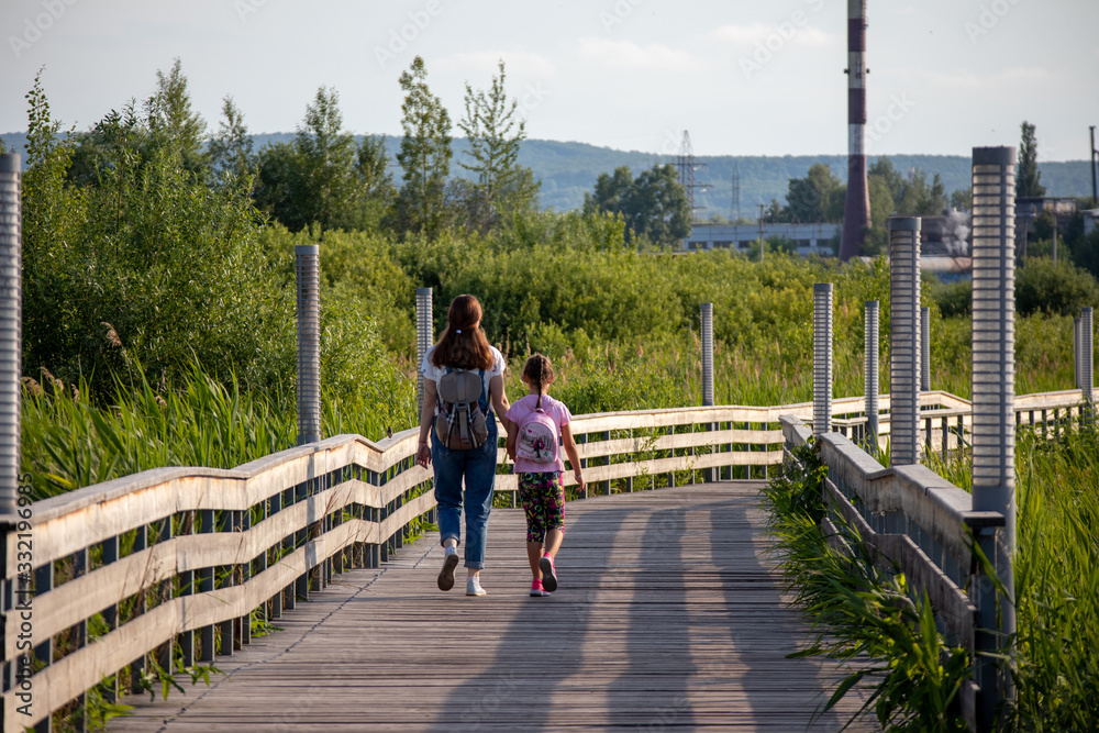 mom and daughter walking on a bridge