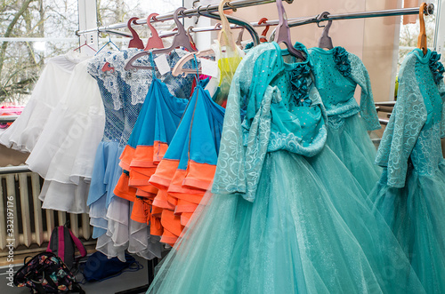 A row of stage costumes for upcoming performances by dance actors hangs on a floor hanger. photo