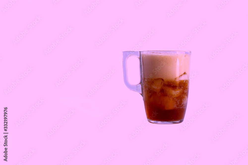 a mug is poured into it. Added ice cubes. Close-up. On a pink background. a mug is poured into it. Added ice cubes. Close-up. On a pink background.
