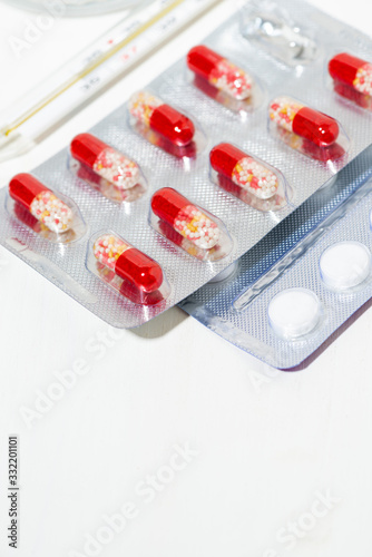 medicines in tablets and capsules, a thermometer, vertical photo