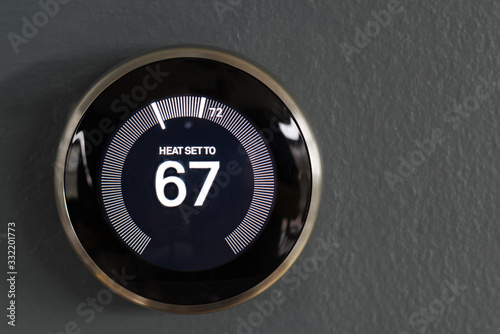 Smart home thermostat from google's nest. Green tech saving heating and cooling costs. Waste reduction photo