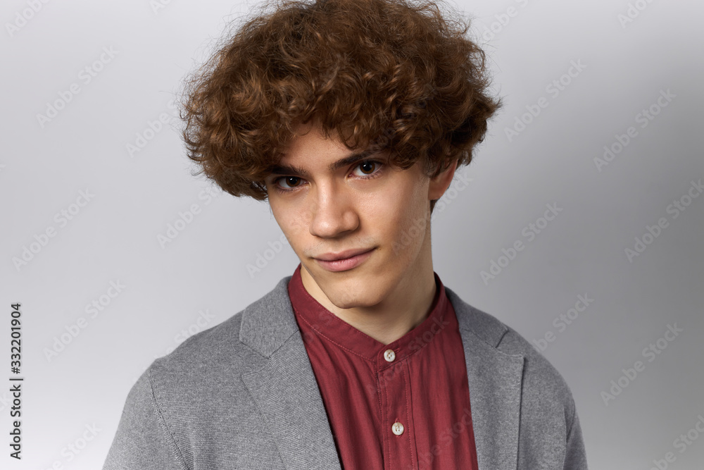 Isolated shot of handsome young Caucasian man with shaved face and voluminous brown hair staring at camera with mysterious or confident facial expression. People, lifestyle and youth concept Isolated shot of handsome young Caucasian man with shaved face and voluminous brown hair staring at camera with mysterious or confident facial expression. People, lifestyle and youth concept