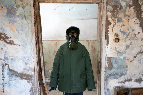 Dramatic portrait of a woman wearing a gas mask in a ruined building.