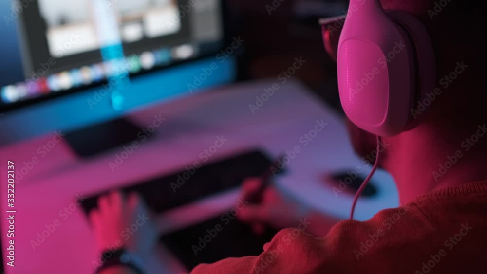 Start of work on new project at home office. Bearded student puts on headphones. Portrait creative man indoors with colourful neon lights. Surfing internet social media studying or work online 4K