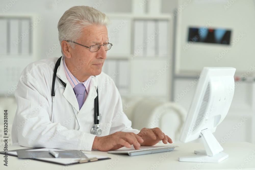 Portrait of senior male doctor working with laptop