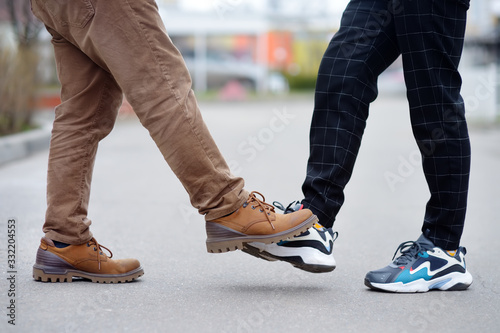 Two men greeting each other with foot instead of handshake. Friends or colleagues touch feet. Alternative non-contact greeting during coronavirus epidemic. Safety during COVID-19 or outbreak. photo