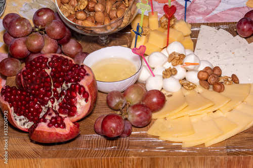 wooden tray with cheese fruit and nuts, pomegranate and grape photo