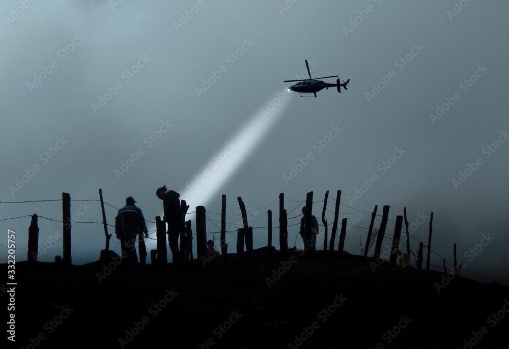 Silhouette of immigrants in the other side of barbed wire and helicopter flash them in the air... - obrazy, fototapety, plakaty 