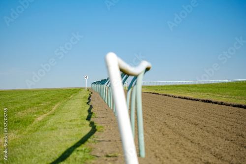 Shallow focus of a race horse trackside fencing seen adjacent to the soft textured race course surface. Seen ascending a hill near a famous english town. photo