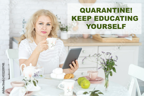 A 50-year-old woman studies at home, reads a book, studies materials. Online learning. Quarantine. Coronavirus. Stay at home. Concept. Self-education. KEY keep educating yourself.