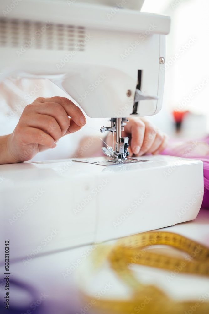 Seamstress woman threading a white thread into a needle. Presser foot close-up