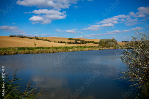 Landscape of Moravian fields with a pond and a beautiful blue sky with white clouds