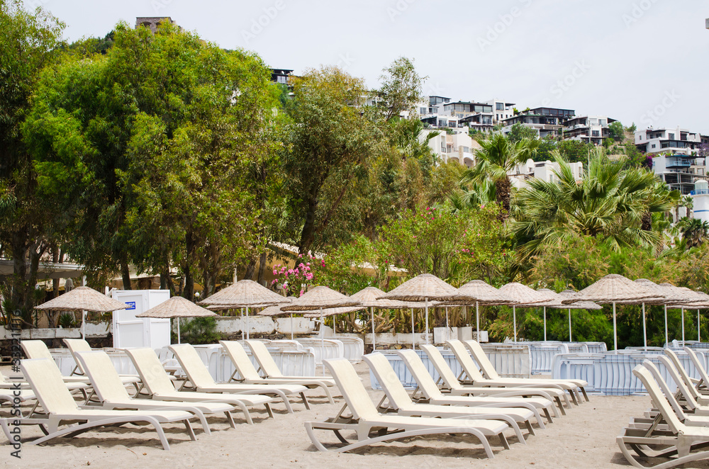 Fototapeta premium Rows of empty sun loungers and umbrellas on the beach. Camel Beach in Turkey.