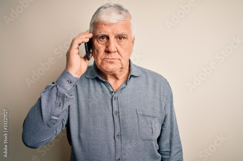 Senior hoary man having conversation talking on the smartphone over white background with a confident expression on smart face thinking serious © Krakenimages.com