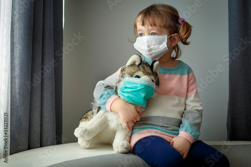 Quarantine at kindergarten. Toddler girl and her dog toy with protection masks. Coronavirus epidemic. Face mask for protection coronavirus outbreak. Medicine healthcare mask photo