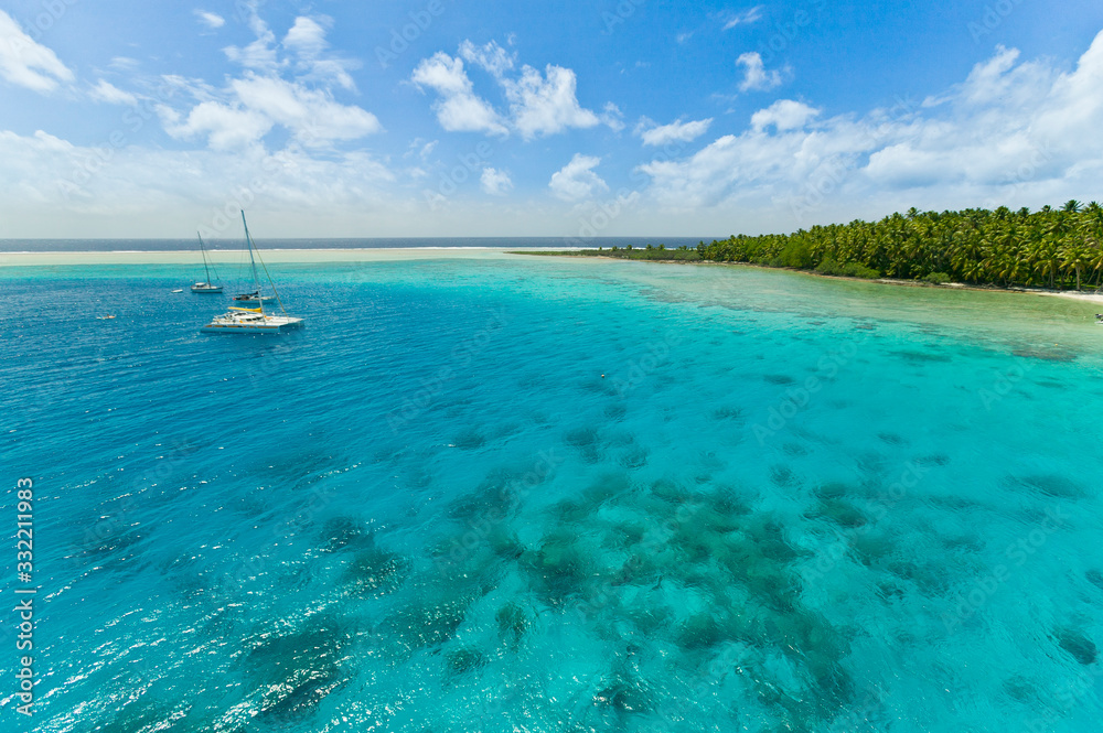 Sailing yacht anchoring in the shallow waters of suwarrow atoll, cook islands, polynesia, pacific ocean