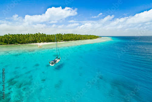 Sailing yacht anchoring in the shallow waters of suwarrow atoll, cook islands, polynesia, pacific ocean photo