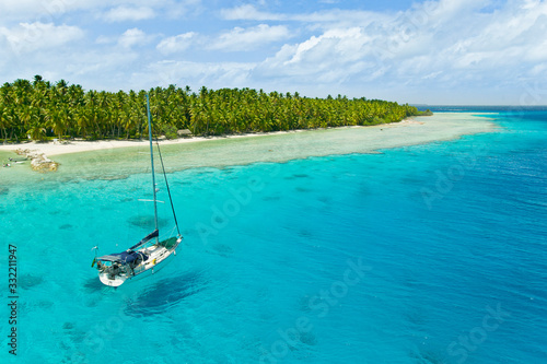 Sailing yacht anchoring in the shallow waters of suwarrow atoll, cook islands, polynesia, pacific ocean
