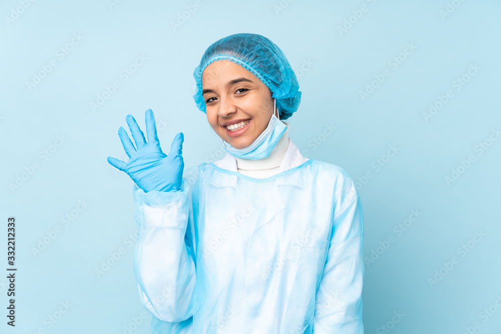 Young surgeon Indian woman in blue uniform counting five with fingers