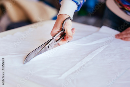 Girl cuts a white cloth with scissors on the table