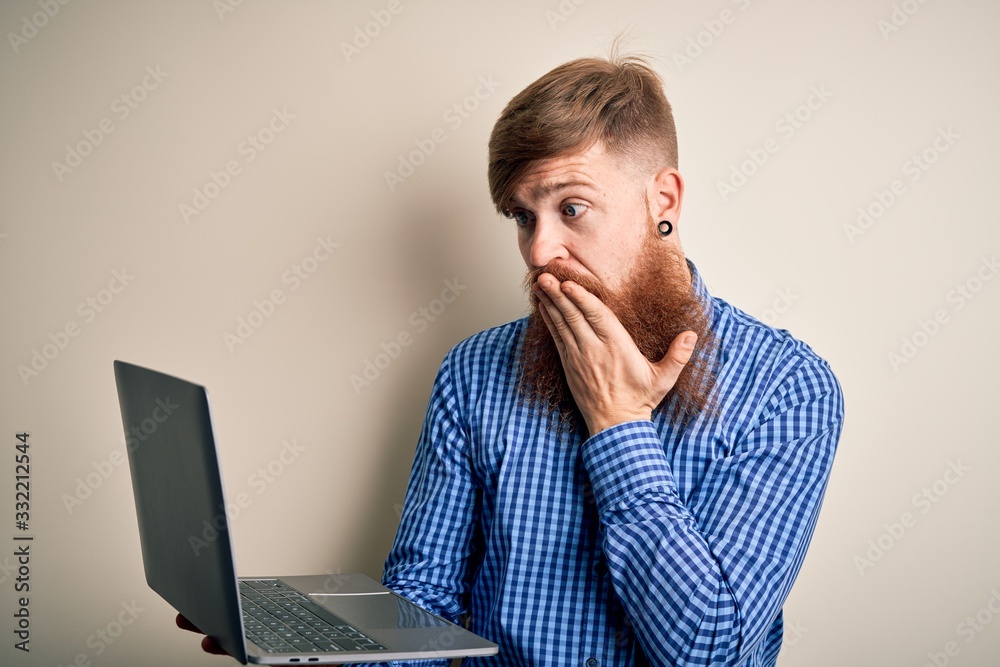Redhead Irish business man with beard using computer laptop over isolated background cover mouth with hand shocked with shame for mistake, expression of fear, scared in silence, secret concept Redhead Irish business man with beard using computer laptop over isolated background cover mouth with hand shocked with shame for mistake, expression of fear, scared in silence, secret concept